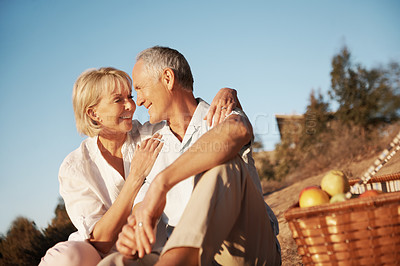 Buy stock photo Picnic, smile or elderly couple in nature with love, partner loyalty or bonding on summer trip. Tender, hug or senior people with fruit basket, romantic relationship or happy moment on outdoor date.