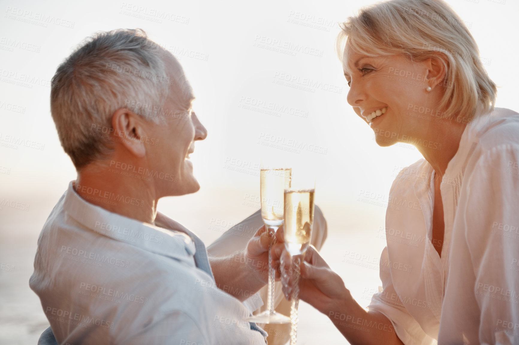 Buy stock photo Couple, happy and cheers at ocean with champagne, celebrate milestone and travel with love. Mature people, smile and toast with drink for bonding, relationship appreciation and commitment at beach