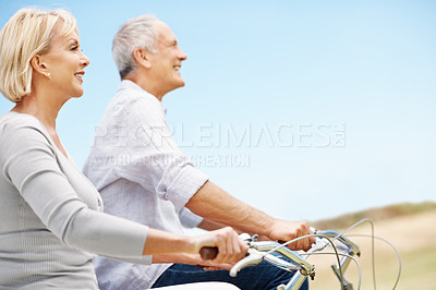 Buy stock photo Freedom, cycling and smile with old couple in nature for bonding, weekend break and anniversary vacation. Retirement, holiday and travel with senior man and woman on bicycle outdoor for space