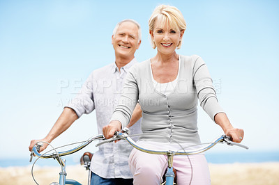Buy stock photo Smile, portrait and senior couple on bike outdoor on vacation, getaway or weekend trip together. Happy, blue sky and elderly man with woman on bicycle for cycling, bonding or adventure on holiday.