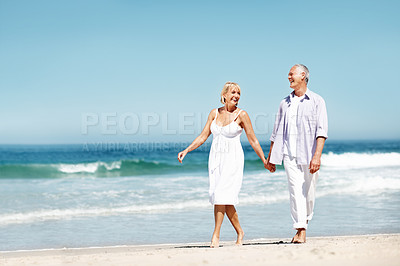 Buy stock photo Couple, happy and holding hands at ocean with love, walking or commitment for anniversary. Space, smile and mature people at beach with affection, marriage milestone or healthy relationship with care