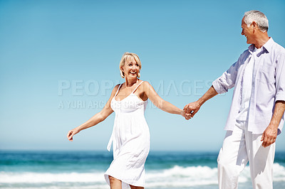 Buy stock photo Couple, happy and holding hands at beach with love, commitment or dancing for anniversary. Space, smile and mature people at ocean with affection, marriage milestone or healthy relationship with care