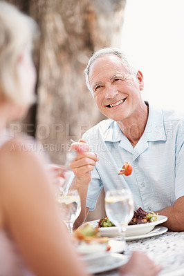 Buy stock photo Senior, couple and happy man eating on date for romance, outdoor dinner or anniversary together. Excited, woman or elderly male person with smile, food or meal for old romantic dining experience