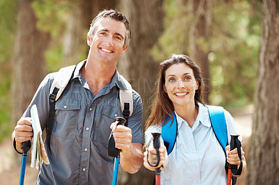 Buy stock photo Portrait, couple and hiking pole in forest with smile, backpack or adventure for bonding on weekend. Happy, married people and walk outdoor in woods with trekking gear, wellness or nature exploration