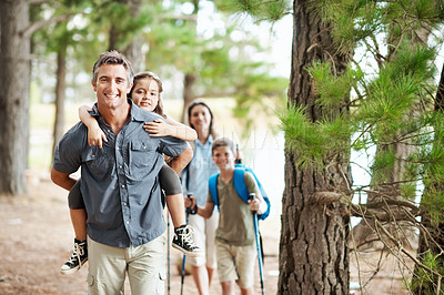 Buy stock photo Portrait, parents and kids hiking with piggyback, smile and adventure outdoor for family in nature. Happy people, mom and dad walk in forest with children, trekking journey and support for bonding.