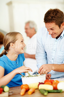 Buy stock photo Father, child and eating food in kitchen with laugh, family gathering and dad joke for bonding together. Happy, man and daughter in home with meal, vegetable salad and humor for Thanksgiving event.