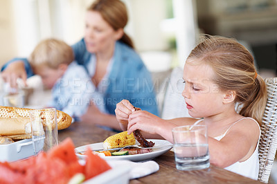 Buy stock photo Child, eating and meal with family in home, hungry or girl with healthy food in dining room or lunch. Childhood, development and kid with steak on table, person and parent with dinner in apartment