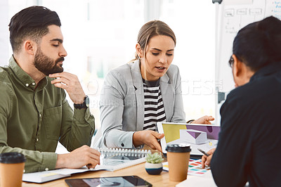 Buy stock photo Shot of young businesspeople using a digital tablet during a meeting in a modern office