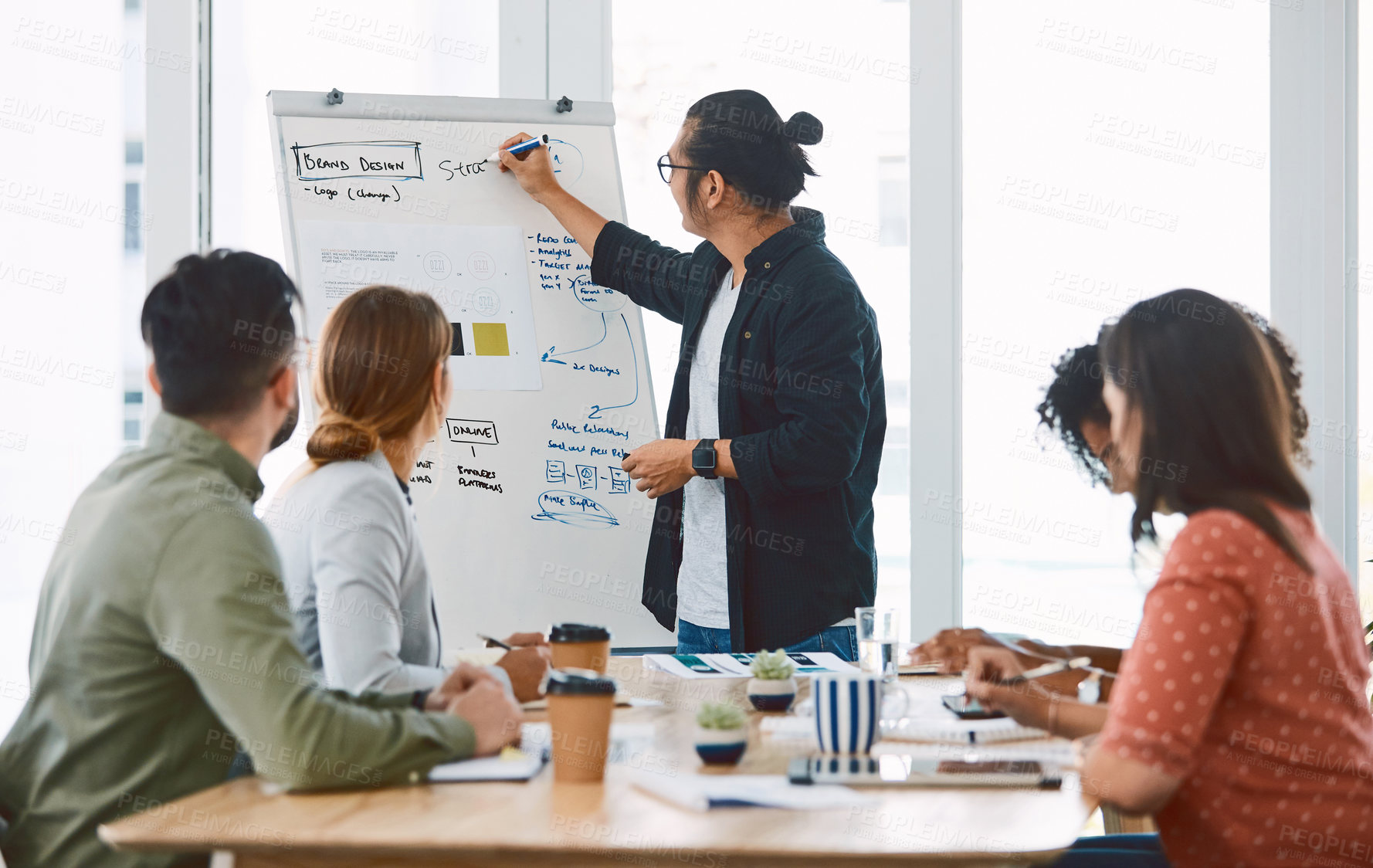 Buy stock photo Shot of a young businessman delivering a presentation to his colleagues in a modern office