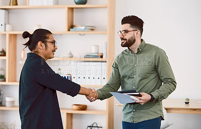 Buy stock photo Shot of two young businessmen shaking hands in a modern office