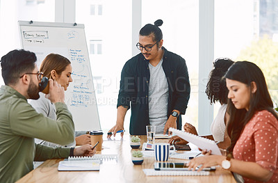 Buy stock photo Shot of a young businessman delivering a presentation to his colleagues in a modern office