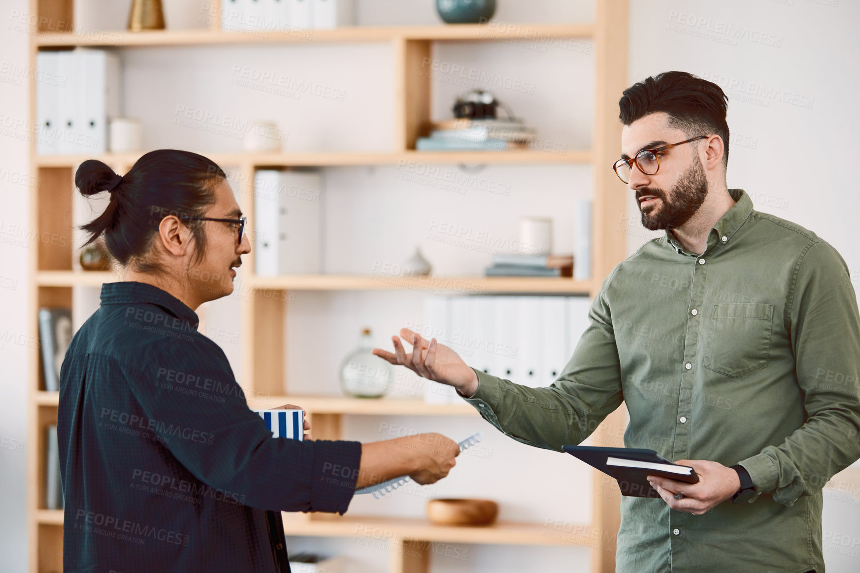 Buy stock photo Shot of two young businessmen having a meeting in a modern office