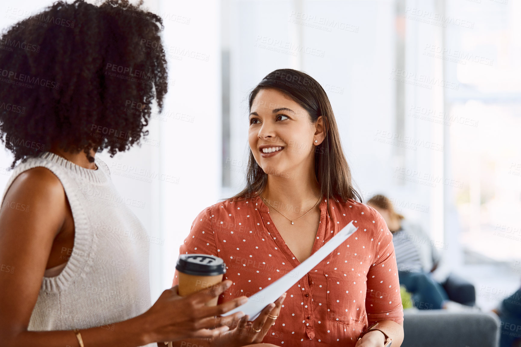 Buy stock photo Shot of two young businesswomen having a discussion in a modern office