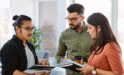 Buy stock photo Shot of young businesspeople using a digital tablet during a meeting in a modern office