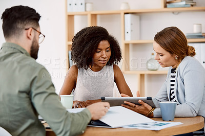 Buy stock photo Shot of young businesspeople using a digital tablet during a meeting in a modern office