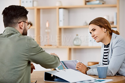 Buy stock photo Shot of young businesspeople using a digital tablet during a meeting in a modern office