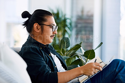 Buy stock photo Shot of a young businessman reading through notes in a modern office