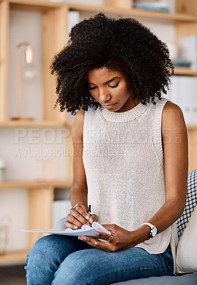 Buy stock photo Shot of a young businesswoman reading through paperwork in a modern office