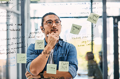 Buy stock photo Shot of a handsome young businessman planning and writing notes on a glass wall in his office