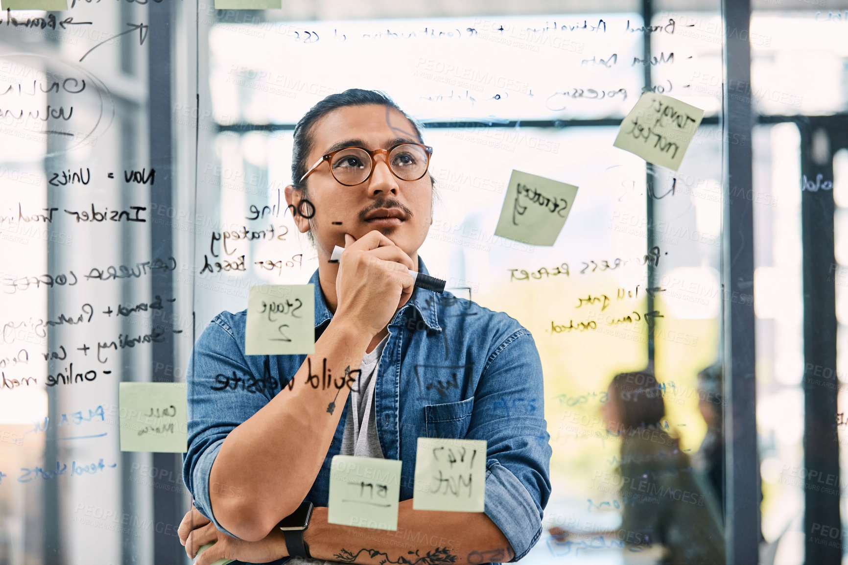 Buy stock photo Shot of a handsome young businessman planning and writing notes on a glass wall in his office