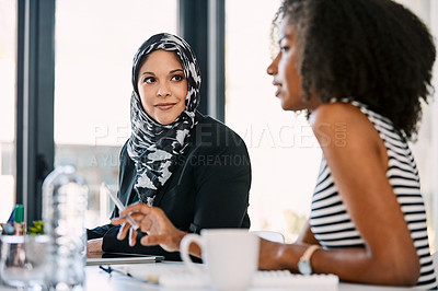 Buy stock photo Shot of two young businesswomen having a meeting together at work