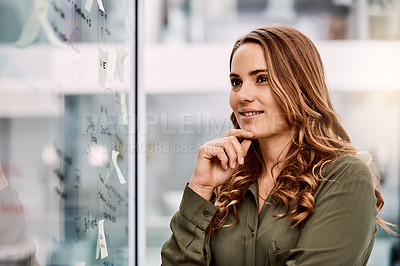 Buy stock photo Shot of an attractive young businesswoman planning and writing notes on a glass wall in her office at work