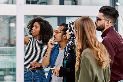 Buy stock photo Shot of a group of young businesspeople planning and writing notes on a glass wall in an office at work