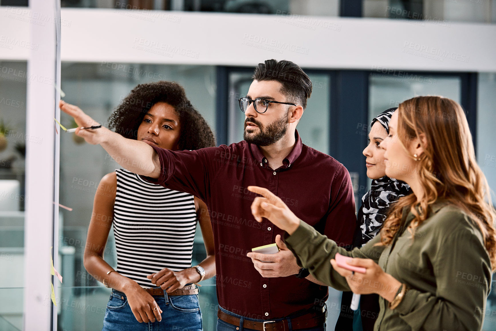 Buy stock photo Shot of a group of young businesspeople planning and writing notes on a glass wall in an office at work