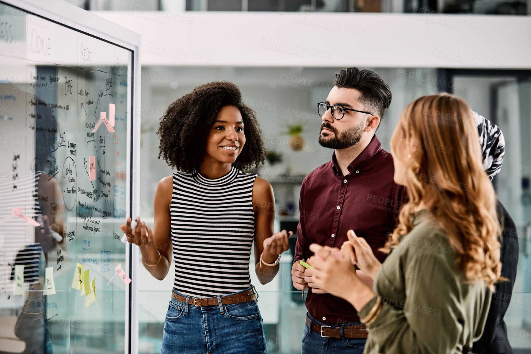 Buy stock photo Shot of a group of young businesspeople planning and writing notes on a glass wall in an office at work