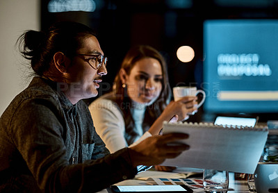 Buy stock photo Shot of a young businessman and businesswoman having a late night meeting at work