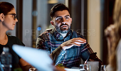 Buy stock photo Shot of a group of young businesspeople having a late night meeting at work