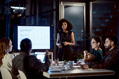 Buy stock photo Shot of a young businesswoman delivering a presentation during a late night meeting at work