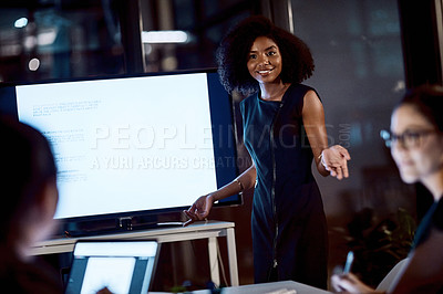 Buy stock photo Shot of a young businesswoman delivering a presentation during a late night meeting at work