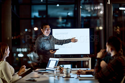 Buy stock photo Shot of a young businessman delivering a presentation during a late night meeting at work