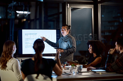 Buy stock photo Shot of a young businessman delivering a presentation during a late night meeting at work