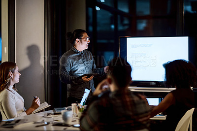 Buy stock photo Shot of a young businessman delivering a presentation during a late night meeting at work