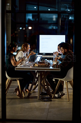 Buy stock photo Shot of a group of young businesspeople having takeout during a late night meeting at work