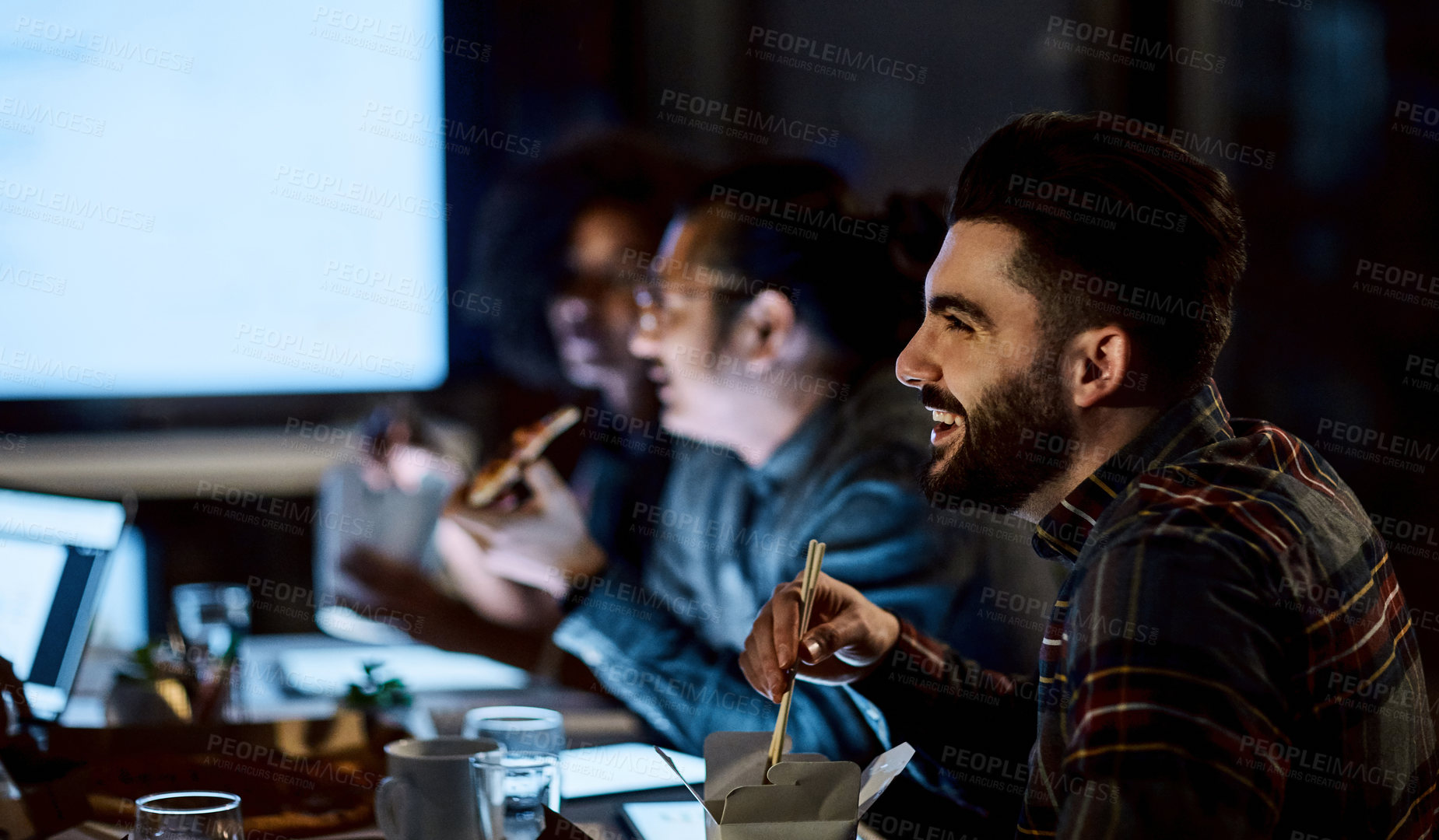 Buy stock photo Shot of a group of young businesspeople having takeout during a late night meeting at work