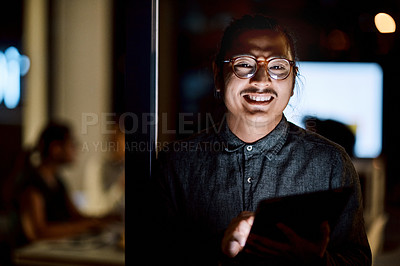 Buy stock photo Shot of a young businessman using a digital tablet during a late night at work