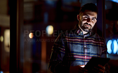 Buy stock photo Shot of a young businessman using a digital tablet during a late night at work