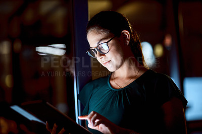 Buy stock photo Shot of a young businesswoman using a digital tablet during a late night at work