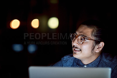 Buy stock photo Shot of a young businessman using a laptop during a late night at work