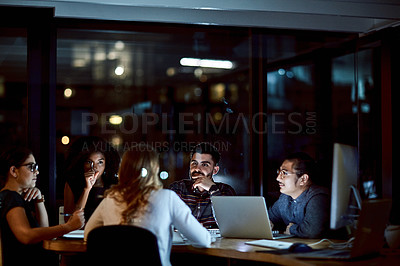 Buy stock photo Shot of a group of young businesspeople having a late night meeting at work