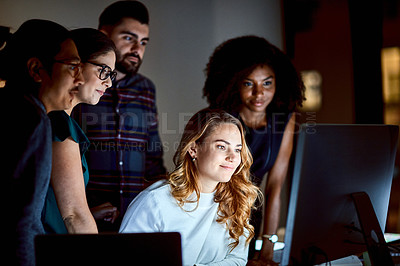 Buy stock photo Shot of a group of young businesspeople using a computer during a late night at work