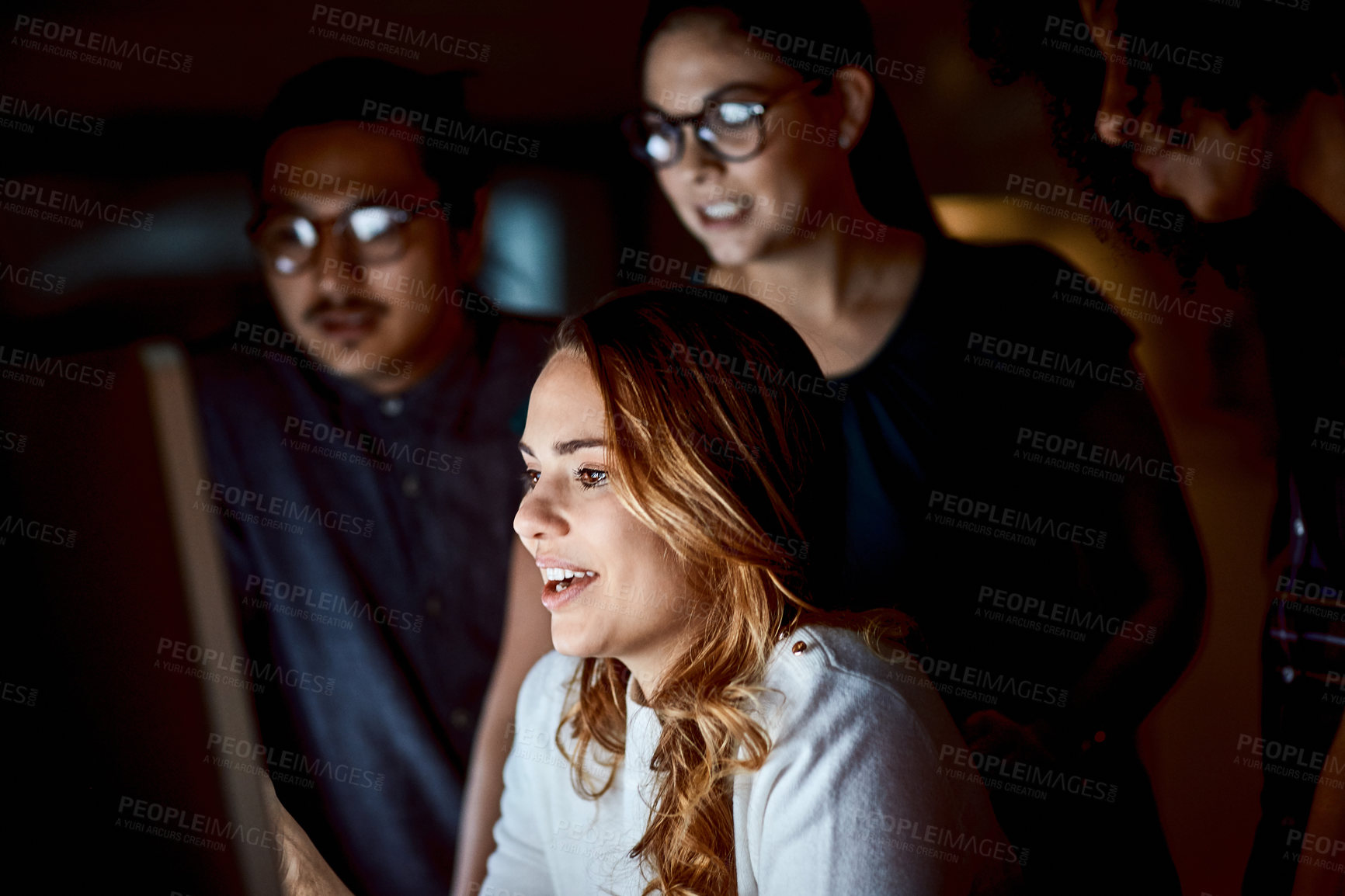 Buy stock photo Shot of a group of young businesspeople using a computer during a late night at work