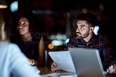 Buy stock photo Shot of a group of young businesspeople having a late night meeting at work