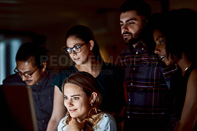 Buy stock photo Shot of a group of young businesspeople using a computer during a late night at work