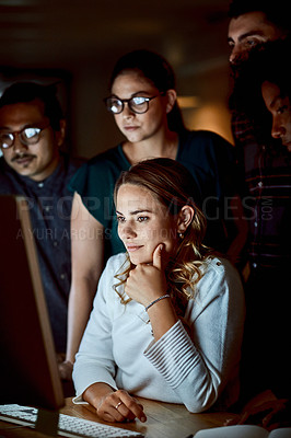 Buy stock photo Shot of a group of young businesspeople using a computer during a late night at work