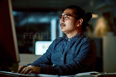 Buy stock photo Shot of a young businessman using a computer during a late night at work
