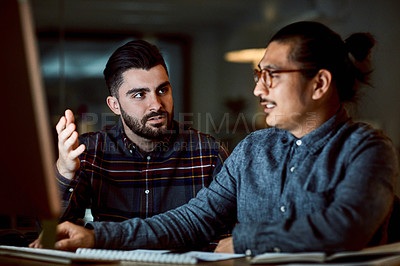 Buy stock photo Shot of two young businessmen using a computer during a late night at work